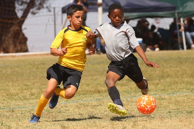 Niños jugando al fútbol con botas de fútbol